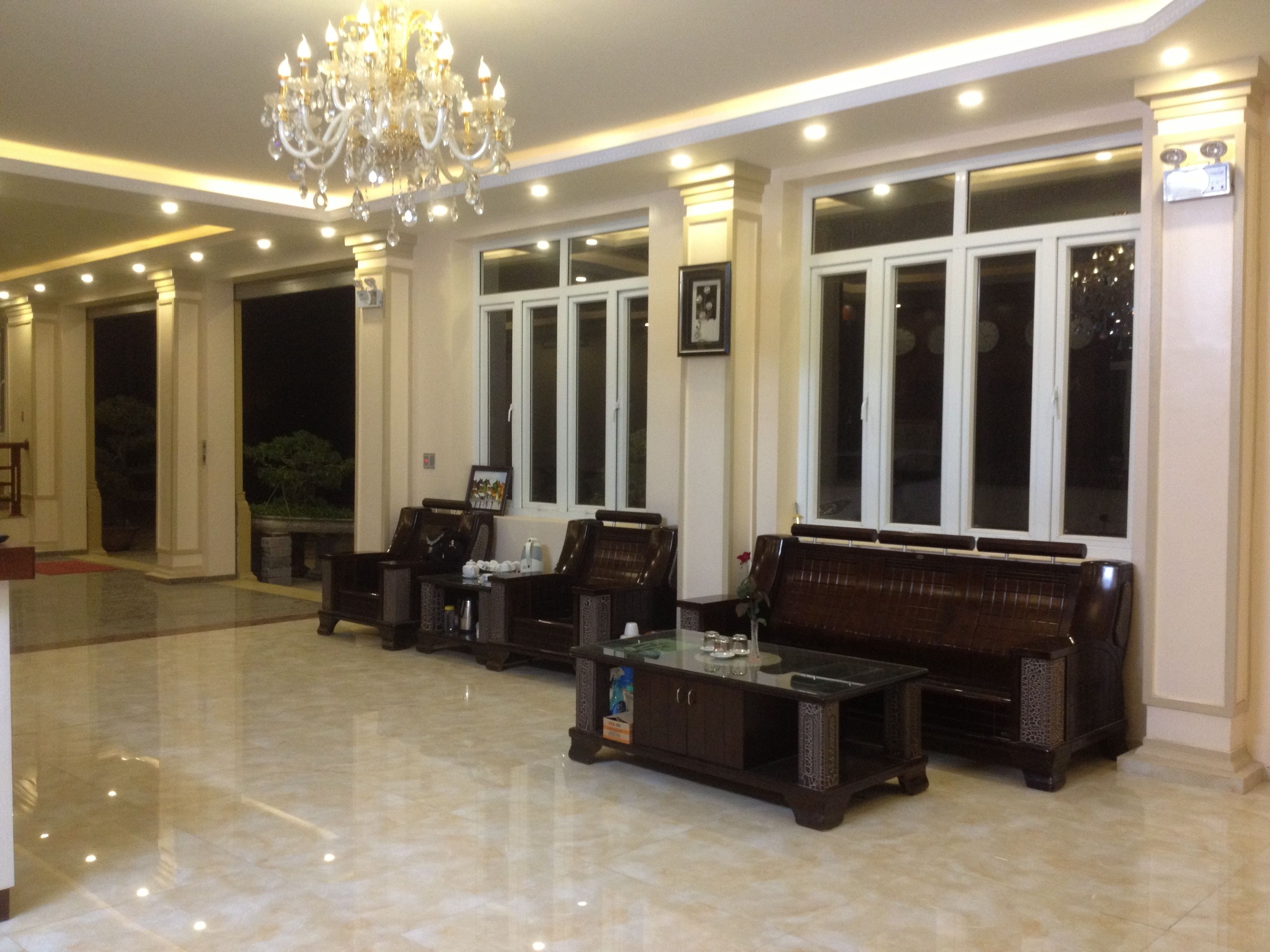 A spacious lobby with a marble floor, large windows, and a chandelier.