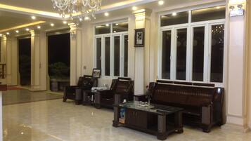 A spacious lobby with a marble floor, large windows, and a chandelier.