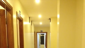 Un pasillo con puertas de madera y suelo de baldosas que conduce a un baño.