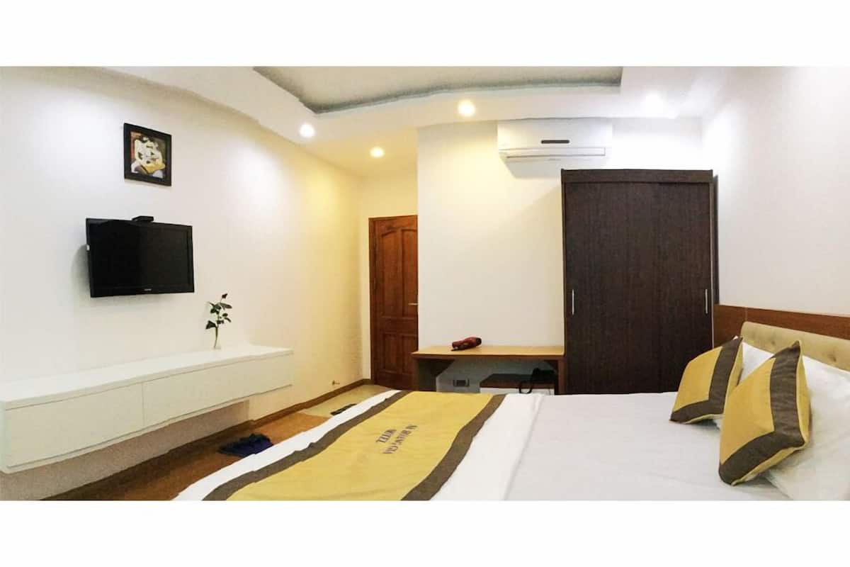 A hotel room with a bed, a desk, a television, and a wardrobe.