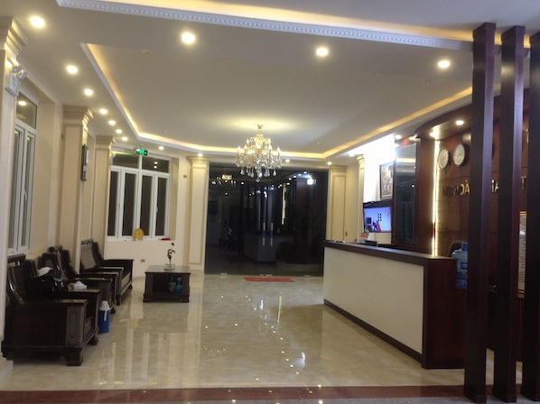 Un vestíbulo de hotel con mostrador de recepción, zona de estar y una araña.