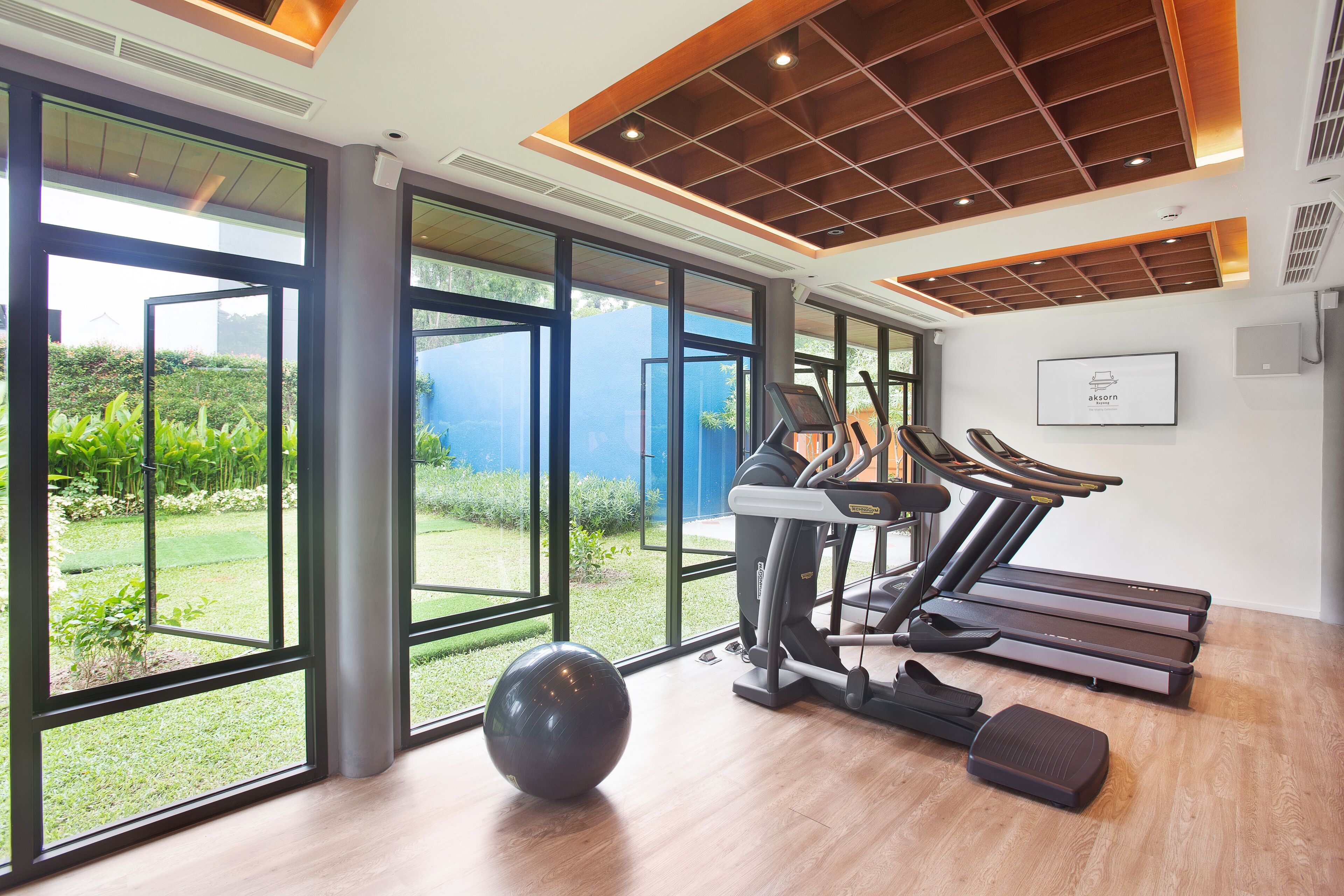 Un gimnasio moderno con amplios ventanales, una cinta de correr y una bicicleta estática.