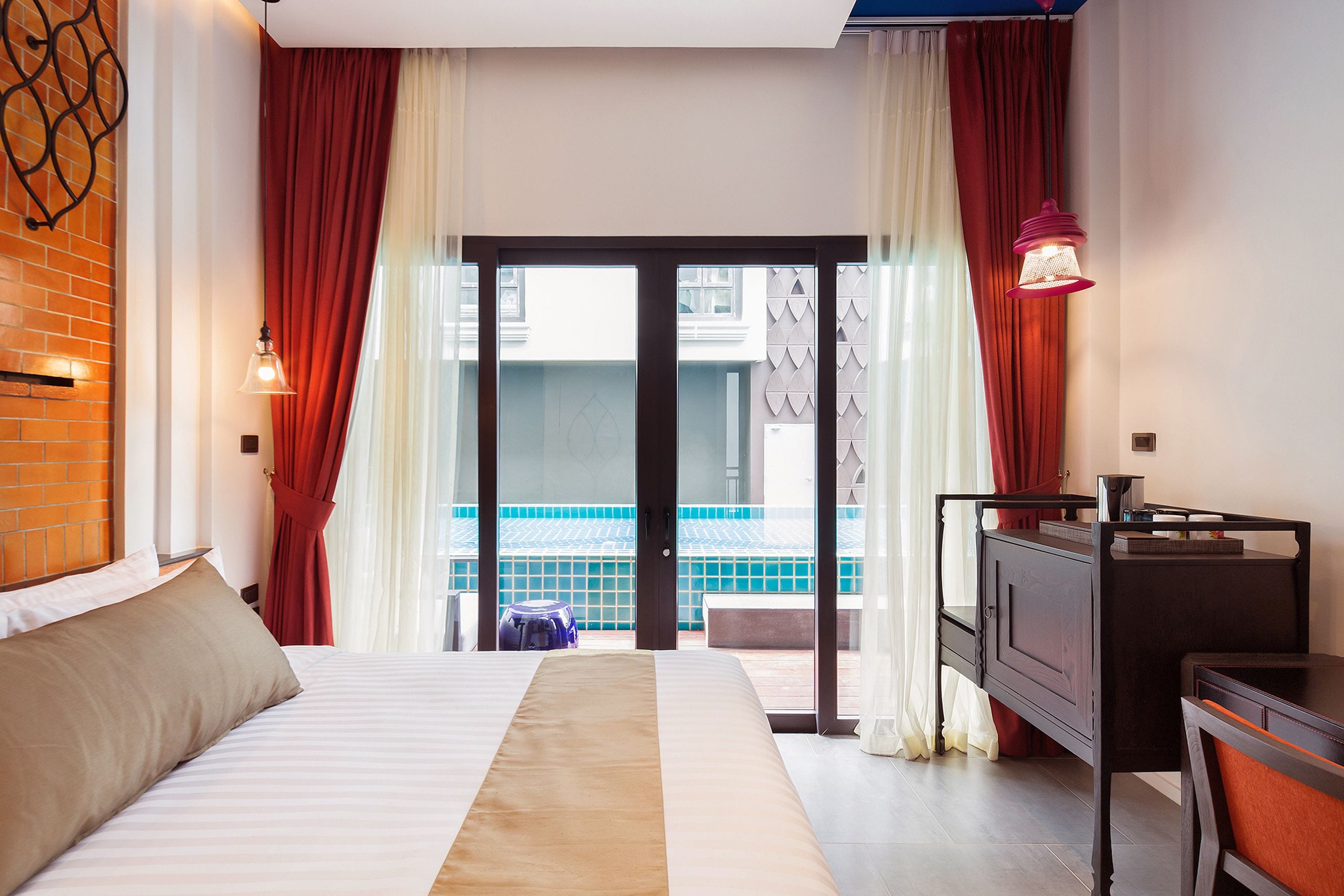 Ein Hotelzimmer mit Bett, Schreibtisch und Blick auf einen Pool durch die Glastüren.