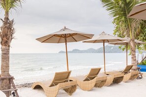 Beach chairs and umbrellas on a sandy shore with a view of the sea and distant islands. - Aksorn Rayong The Vitality Collection (Klaeng)