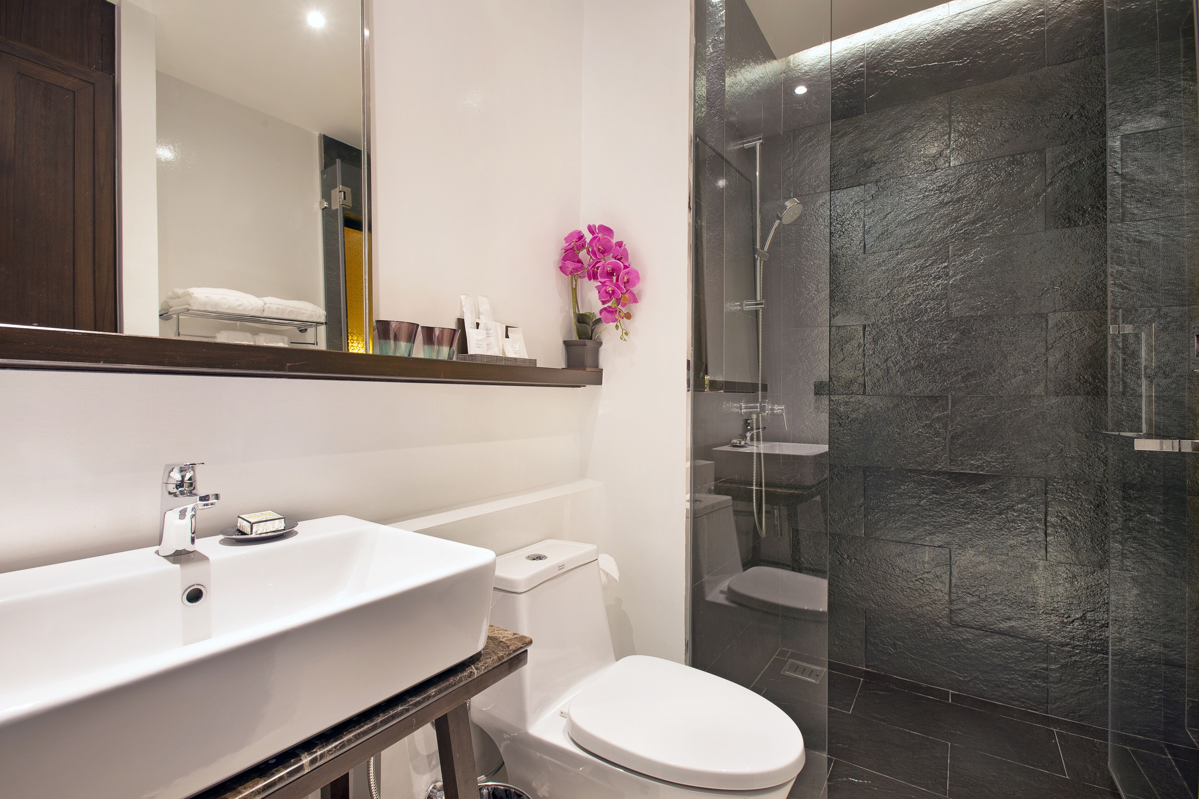 A modern bathroom with a white sink, toilet, and glass-enclosed shower.