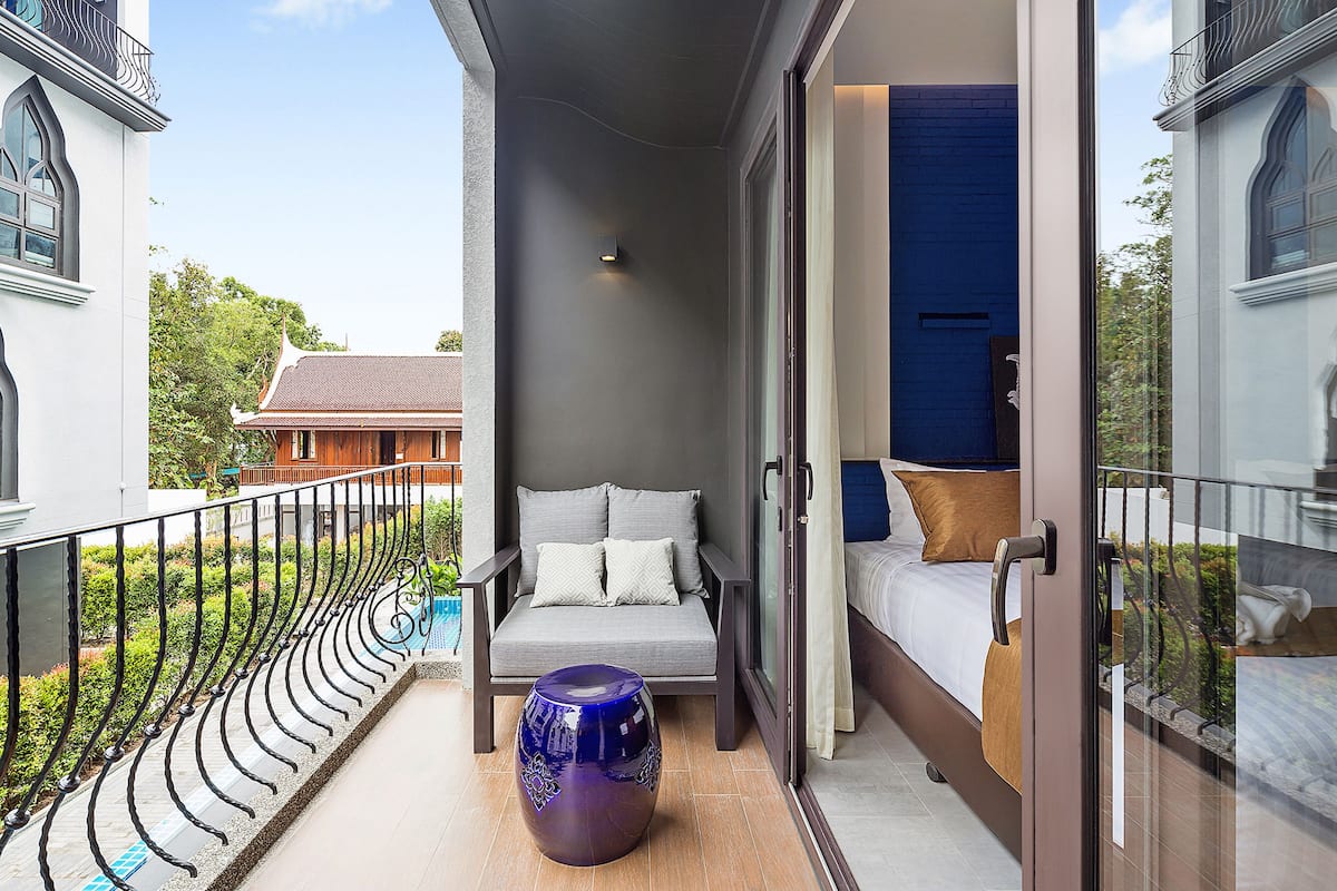 A balcony with a sofa, a decorative vase, and a bed with a view of the surroundings.