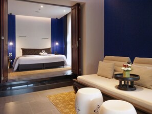 A modern hotel room with a large bed, a sofa, and a small side table with a vase of flowers. - Aksorn Rayong The Vitality Collection (Klaeng)