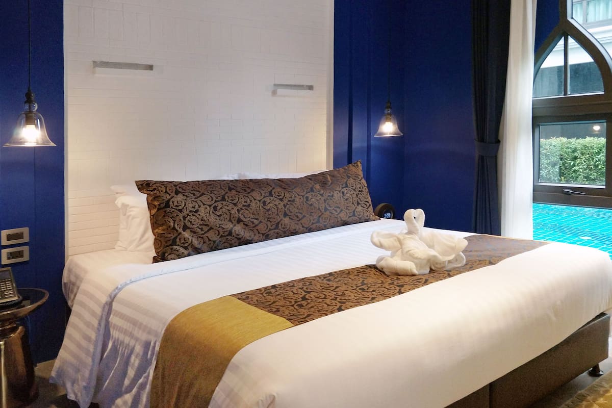 A neatly made bed with a patterned pillow, a white blanket, and a decorative headboard.