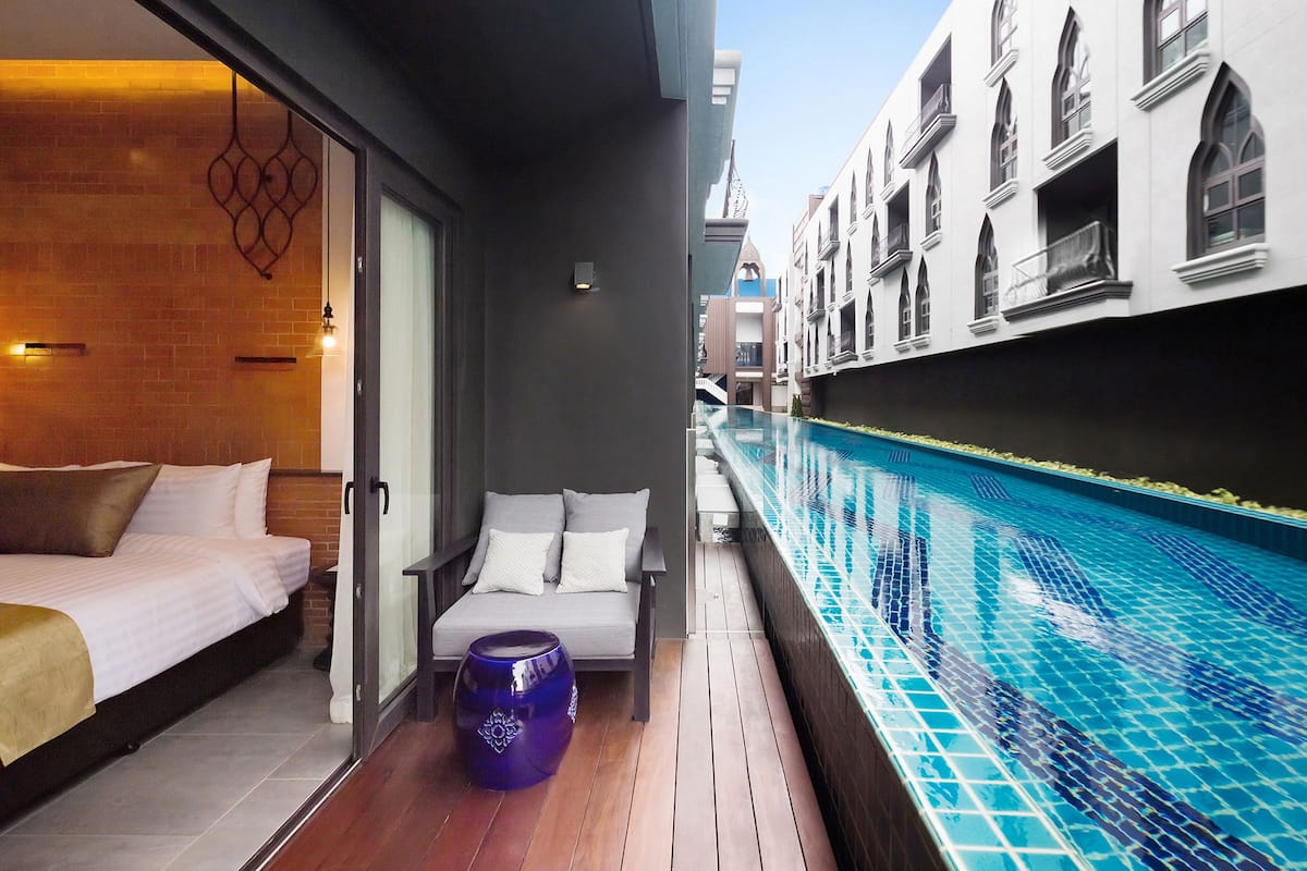 A modern hotel room with a bed, a seating area, and a poolside view.