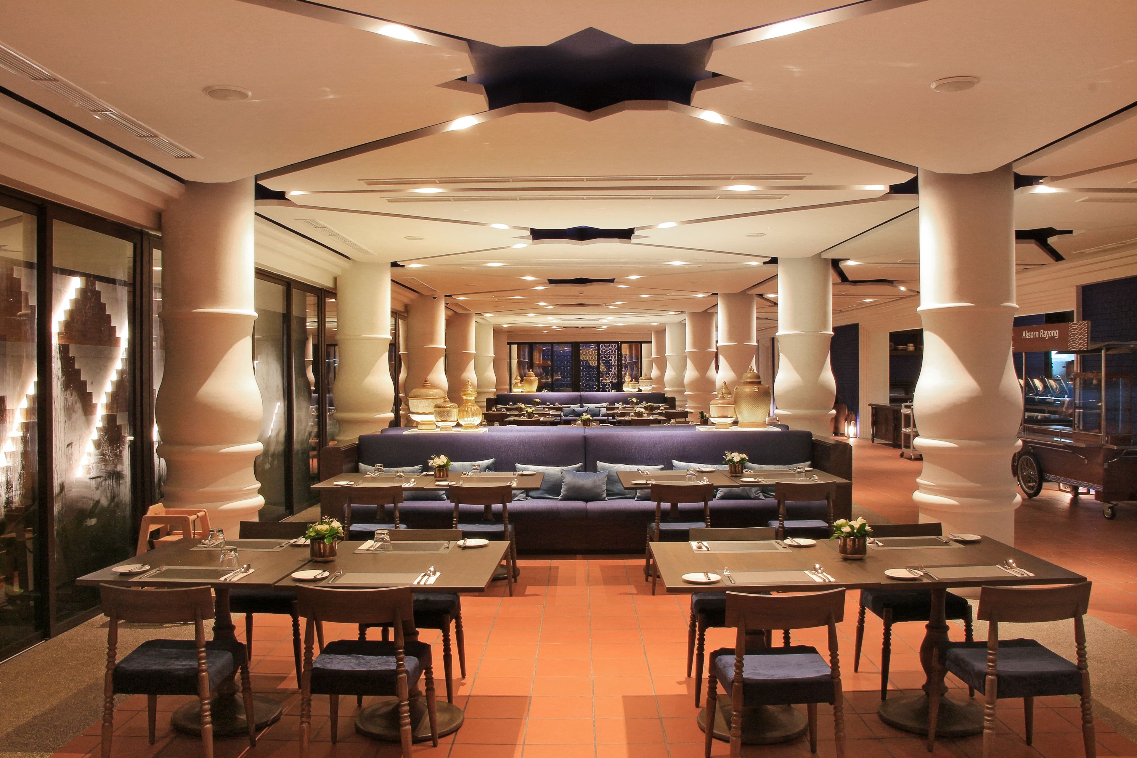 Un restaurante espacioso con techos altos, iluminación moderna y una zona de estar central.
