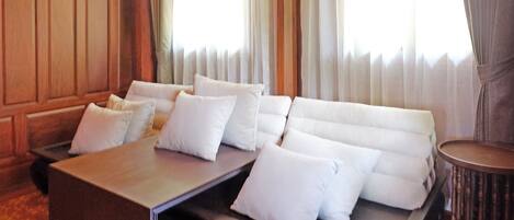 A modern hotel room with a sofa bed, a wooden coffee table, and a small side table.
