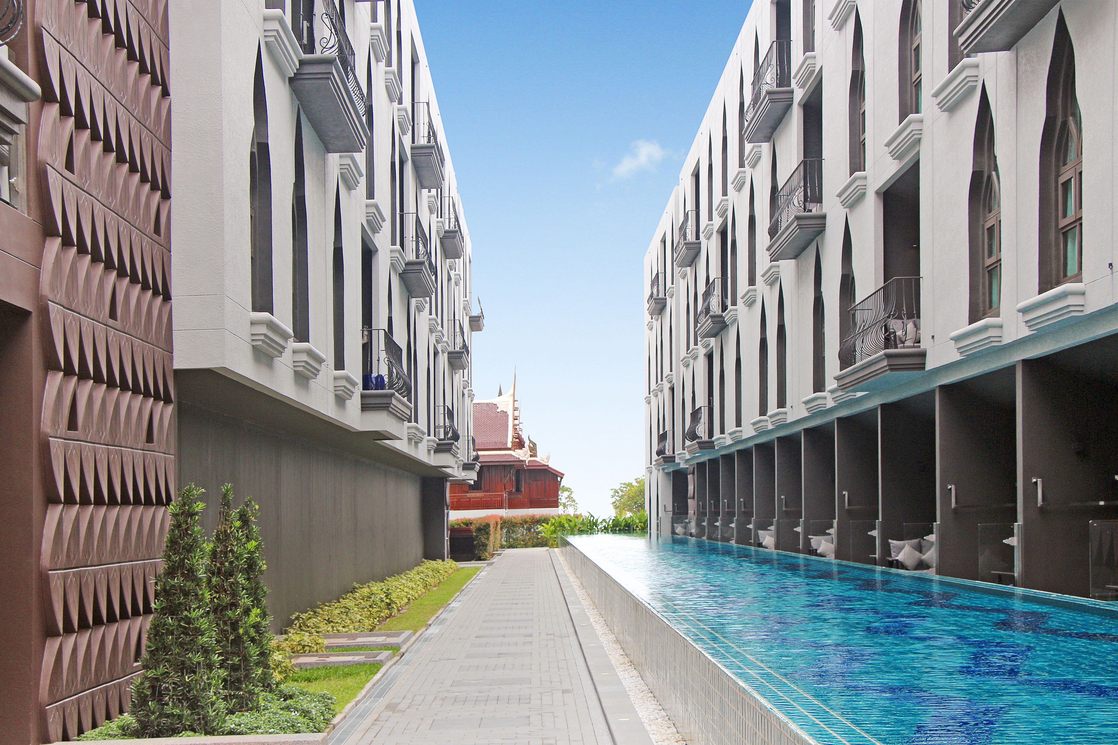 Un couloir d’hôtel, avec une piscine d’un côté et un immeuble doté de balcons de l’autre.