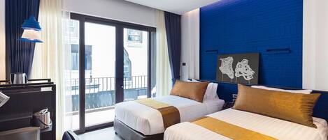 Habitación de hotel con dos camas, un escritorio y vista a la ciudad.