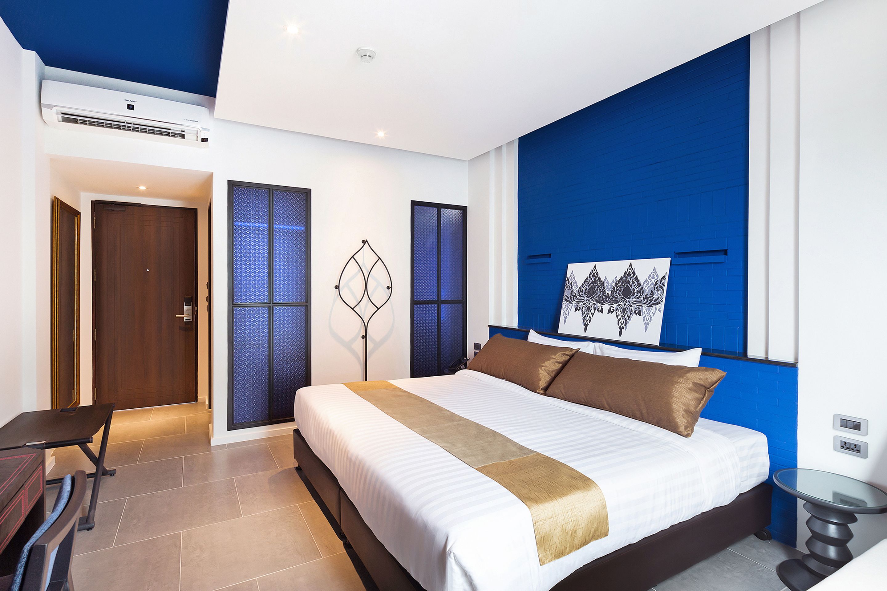 A modern bedroom with a large bed, a desk, and a chair.