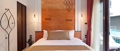 A hotel room with a large bed, a brick wall, and a balcony with a pool.