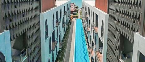 Un hotel moderno con piscina central, múltiples balcones y un diseño arquitectónico simétrico.