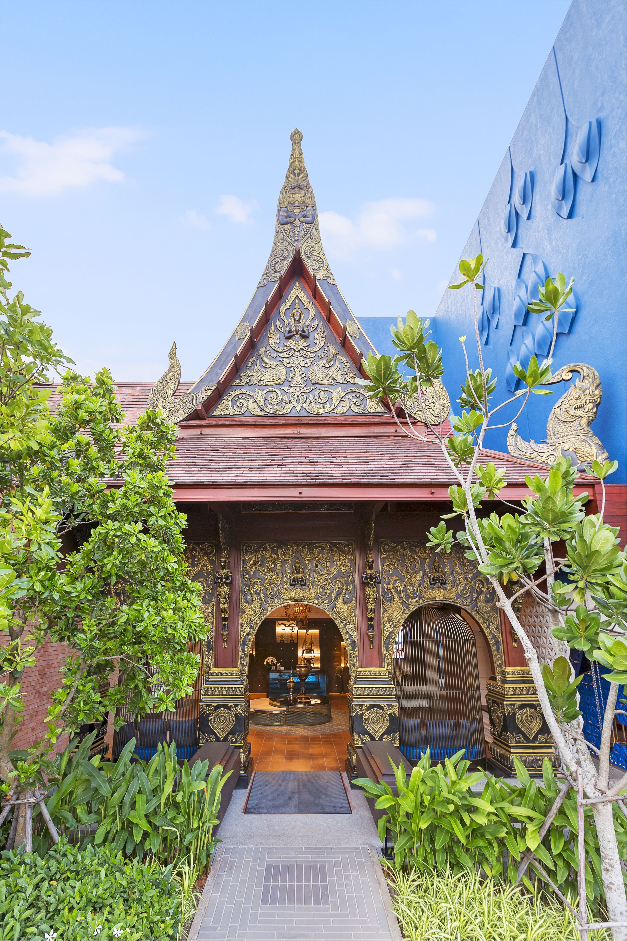 Un bâtiment traditionnel, agrémenté de décorations raffinées, doté d’un porche carrelé et d’un chemin menant à la porte.
