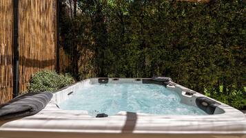 Un jacuzzi con una pérgola de madera y una valla de bambú al fondo.