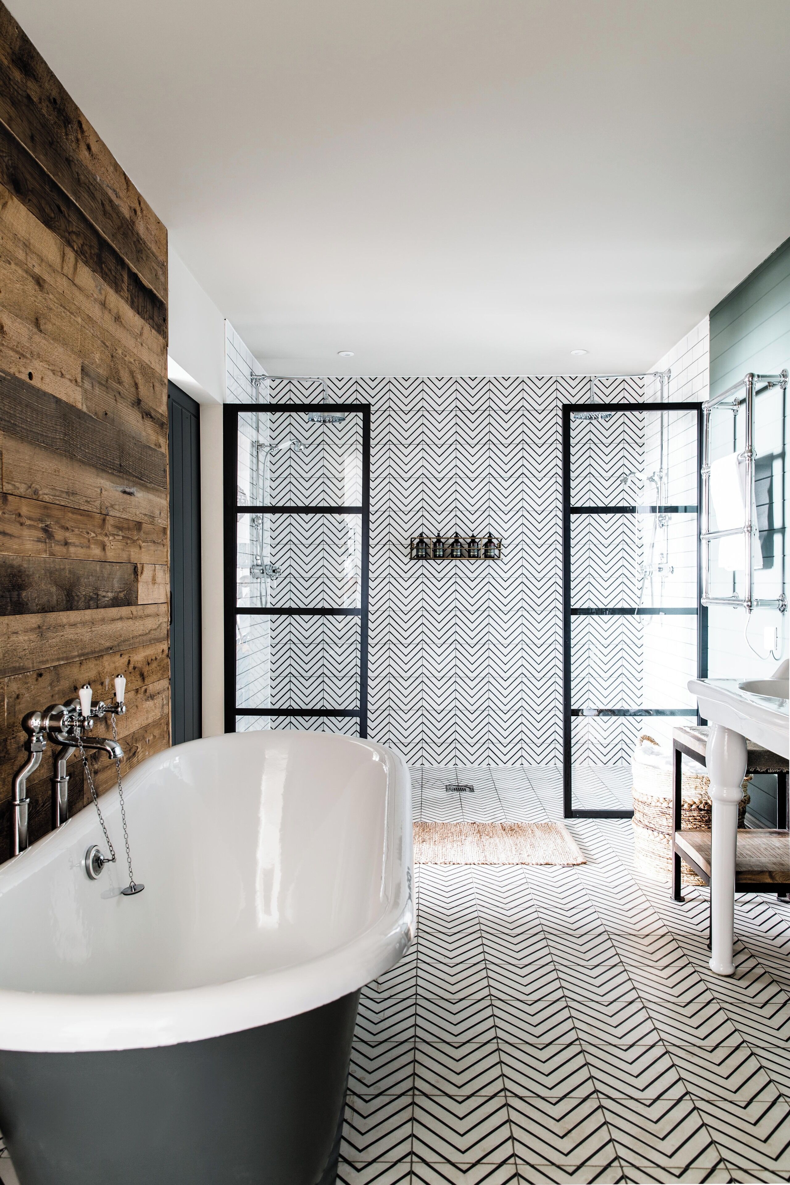 Ein modernes Badezimmer mit freistehender Badewanne, einem großen Spiegel und einem Musterboden.
