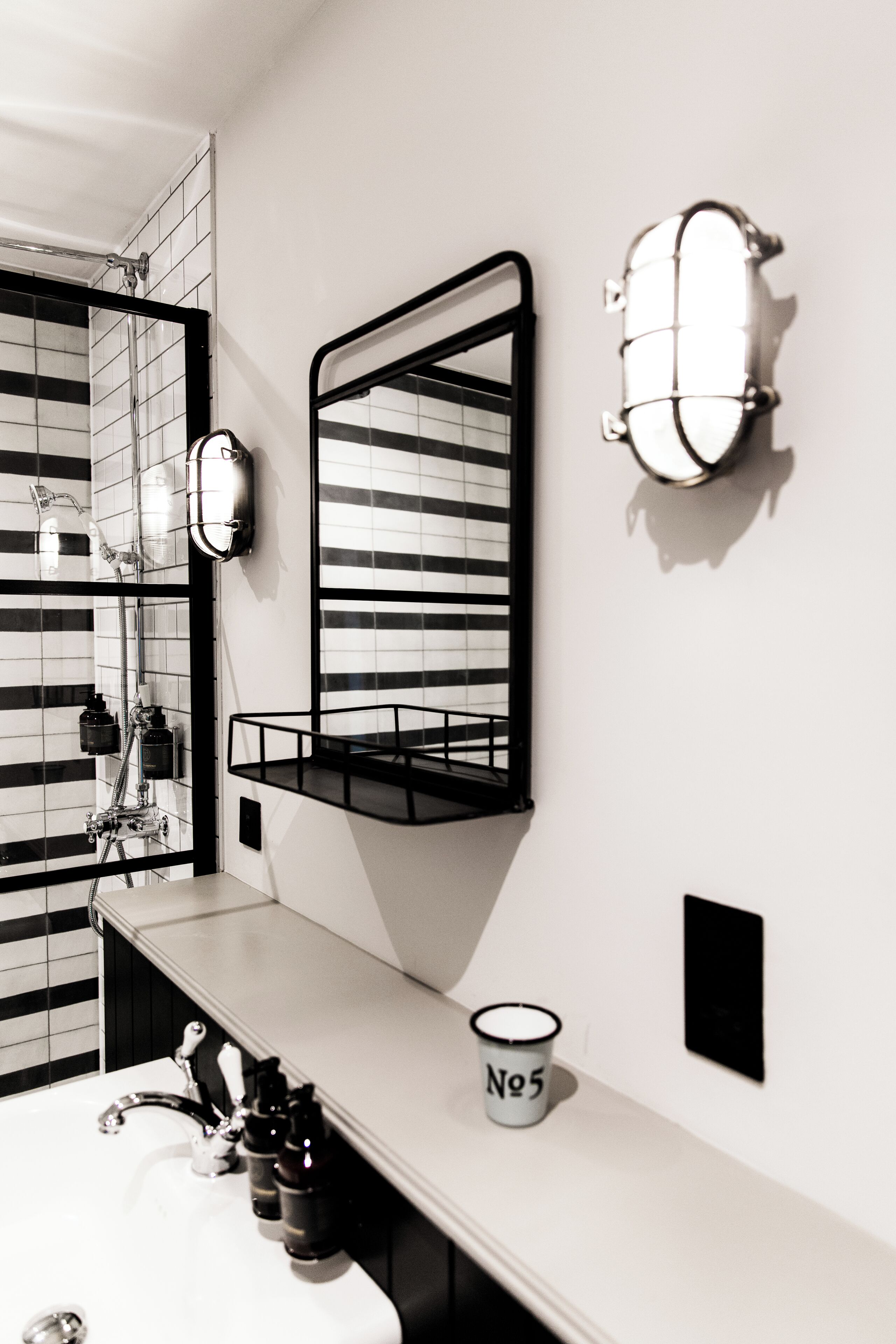 A modern bathroom with a white sink, black-framed mirror, and a towel rack.