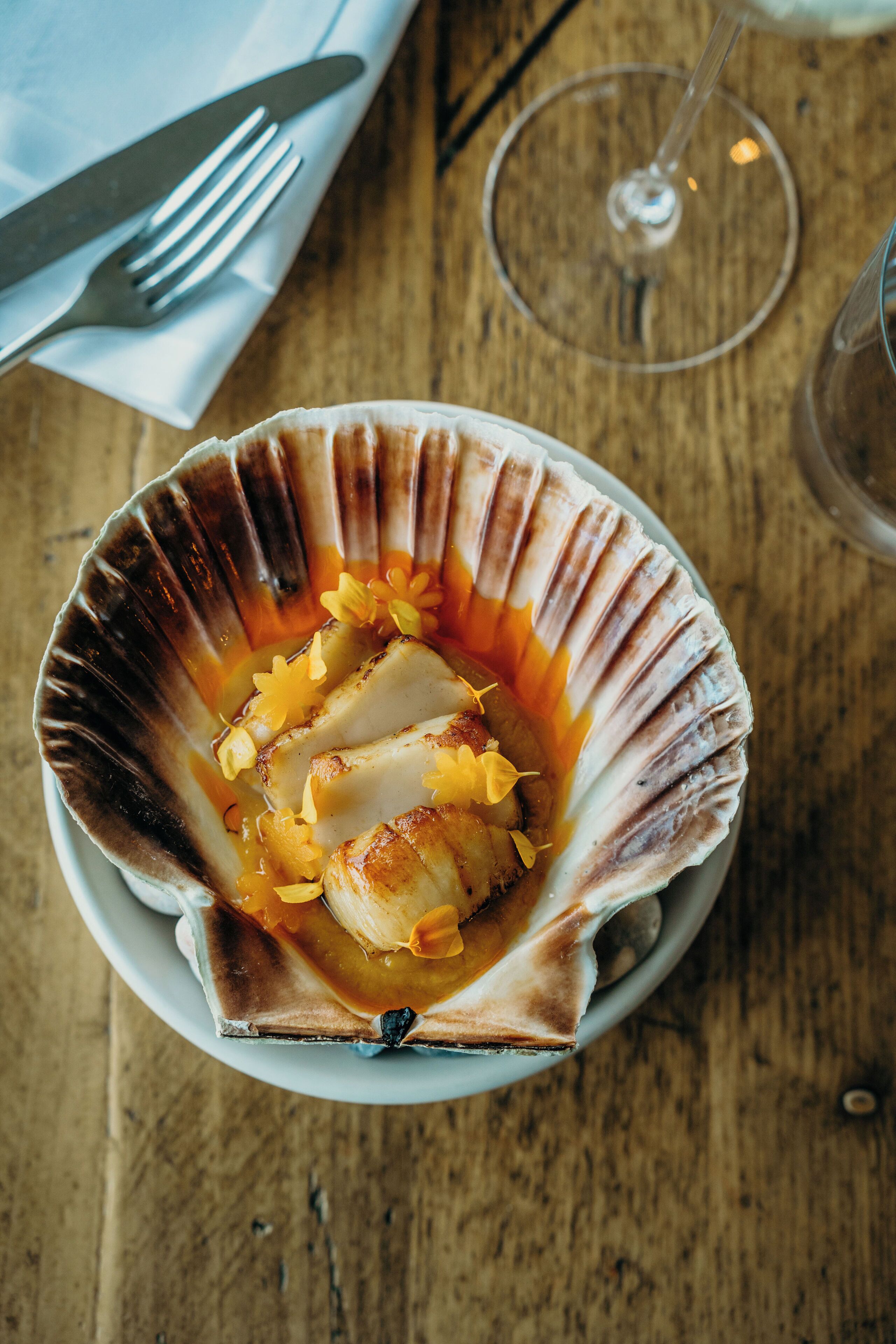 A scallop dish on a plate with a wooden table background.