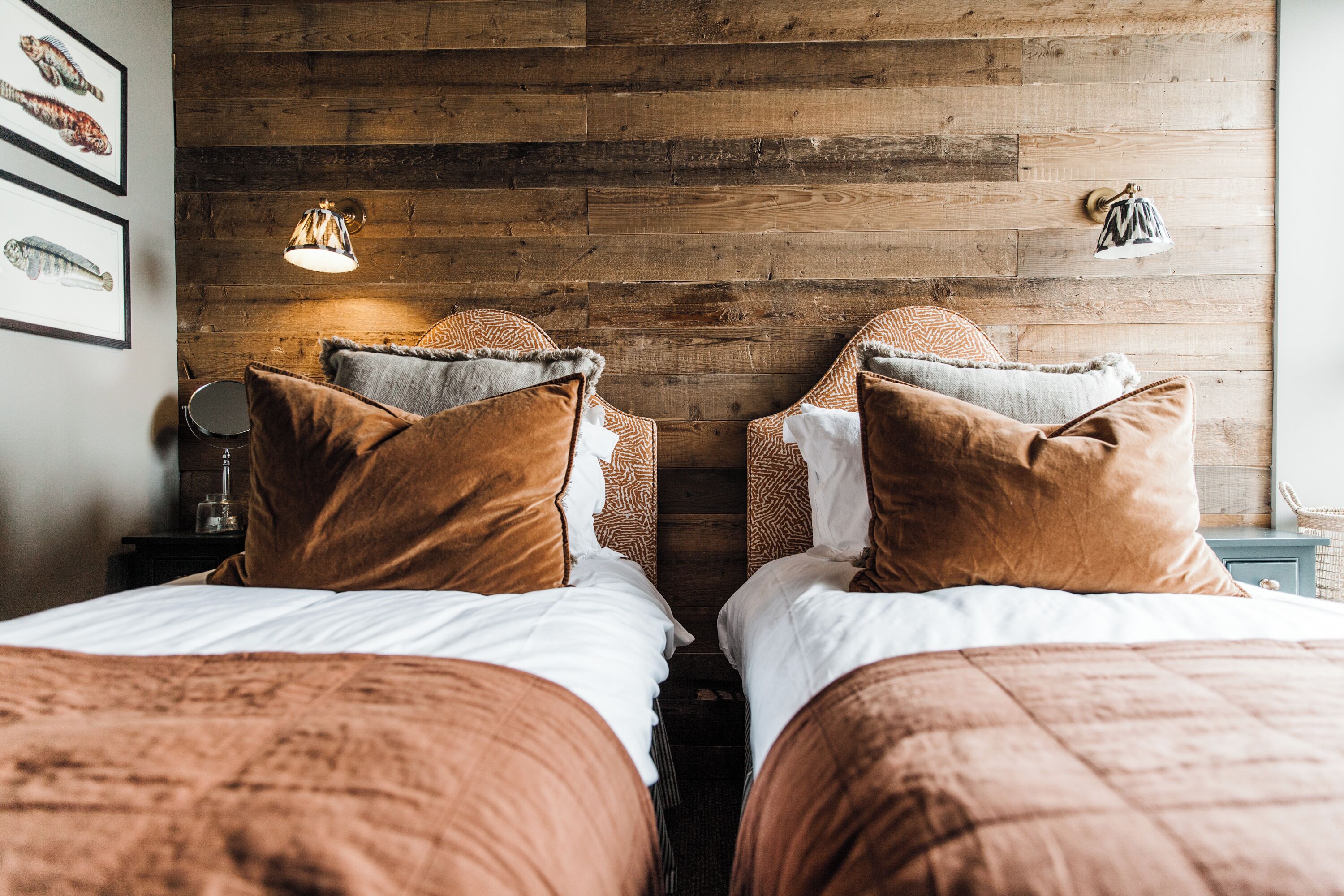 Een slaapkamer met twee bedden, houten wanden en vissenkunst in lijsten.