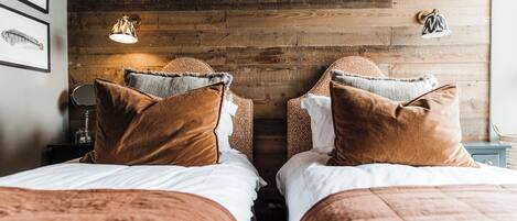 Quarto com duas camas, paredes de madeira e quadros com desenhos de peixes.