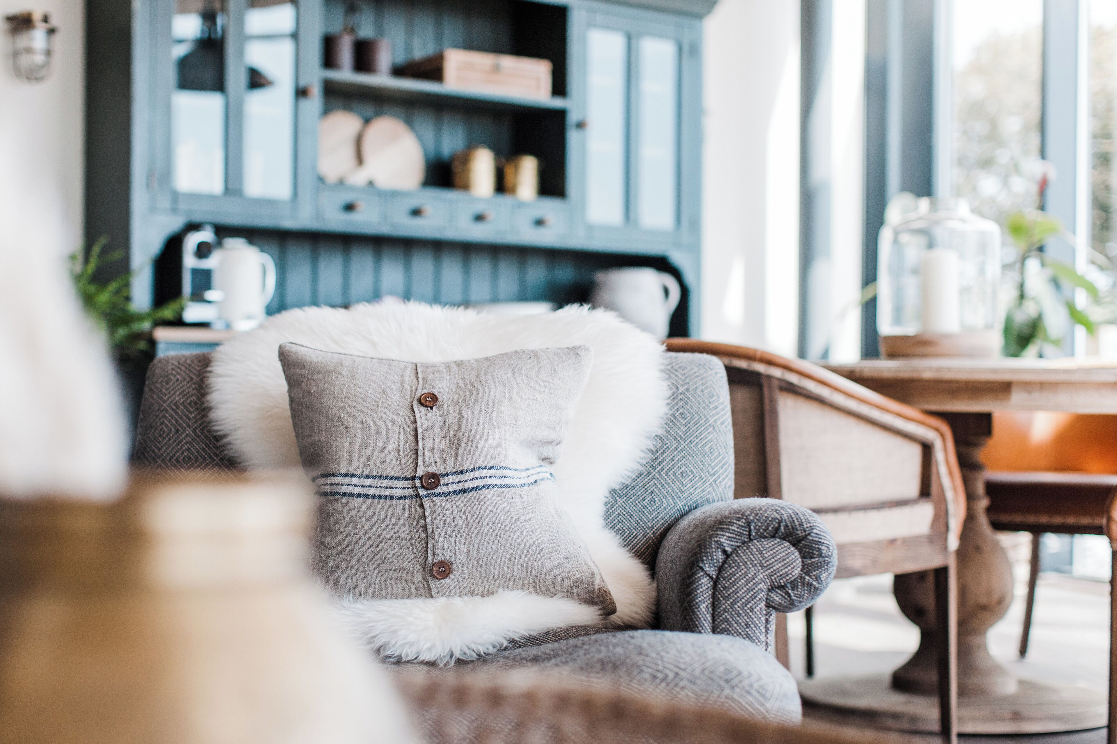 Una sala de estar acogedora con un sofá gris, un almohadón blanco y mullido, y una mesa de centro de madera.