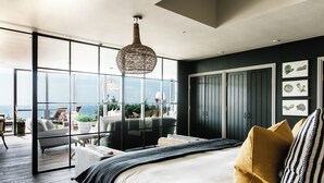 A bedroom with a large bed, a view of the outdoors, and a balcony with seating. - Gara Rock (Salcombe)