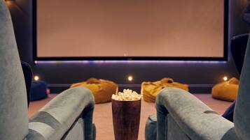 A cozy home theater with plush seating, a popcorn bucket, and a large screen.