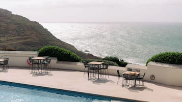 Relax by the pool surrounded by lush greenery and the ocean views.