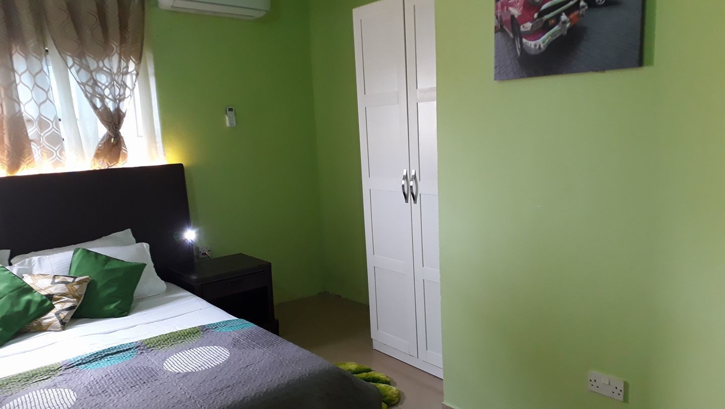 Un dormitorio con cama, mesita de noche, armario y un cuadro en la pared.