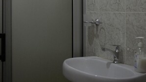 Un bany amb un rentamig blanc, una tovallola penjada a la porta i un mirall decoratiu.