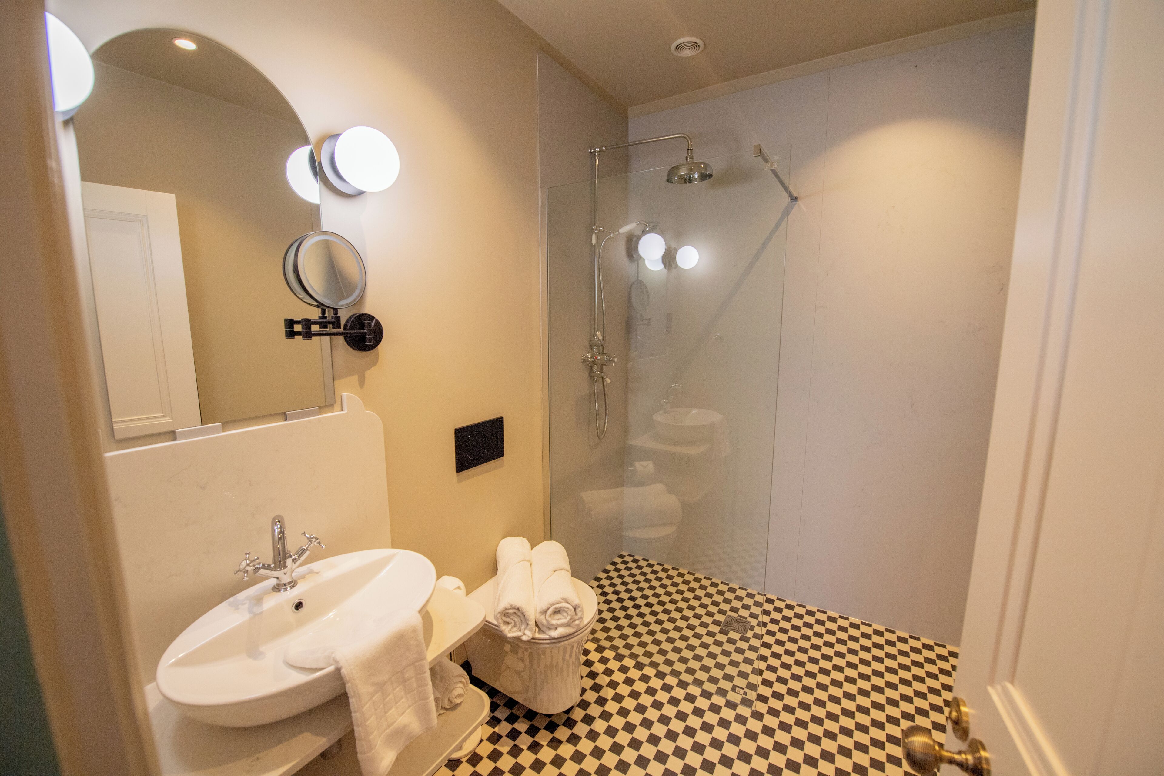 Une salle de bain avec un carrelage à motifs géométriques, un lavabo, un miroir et une douche.