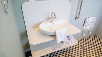 Un baño con lavamanos blanco, toallero y piso a cuadros.