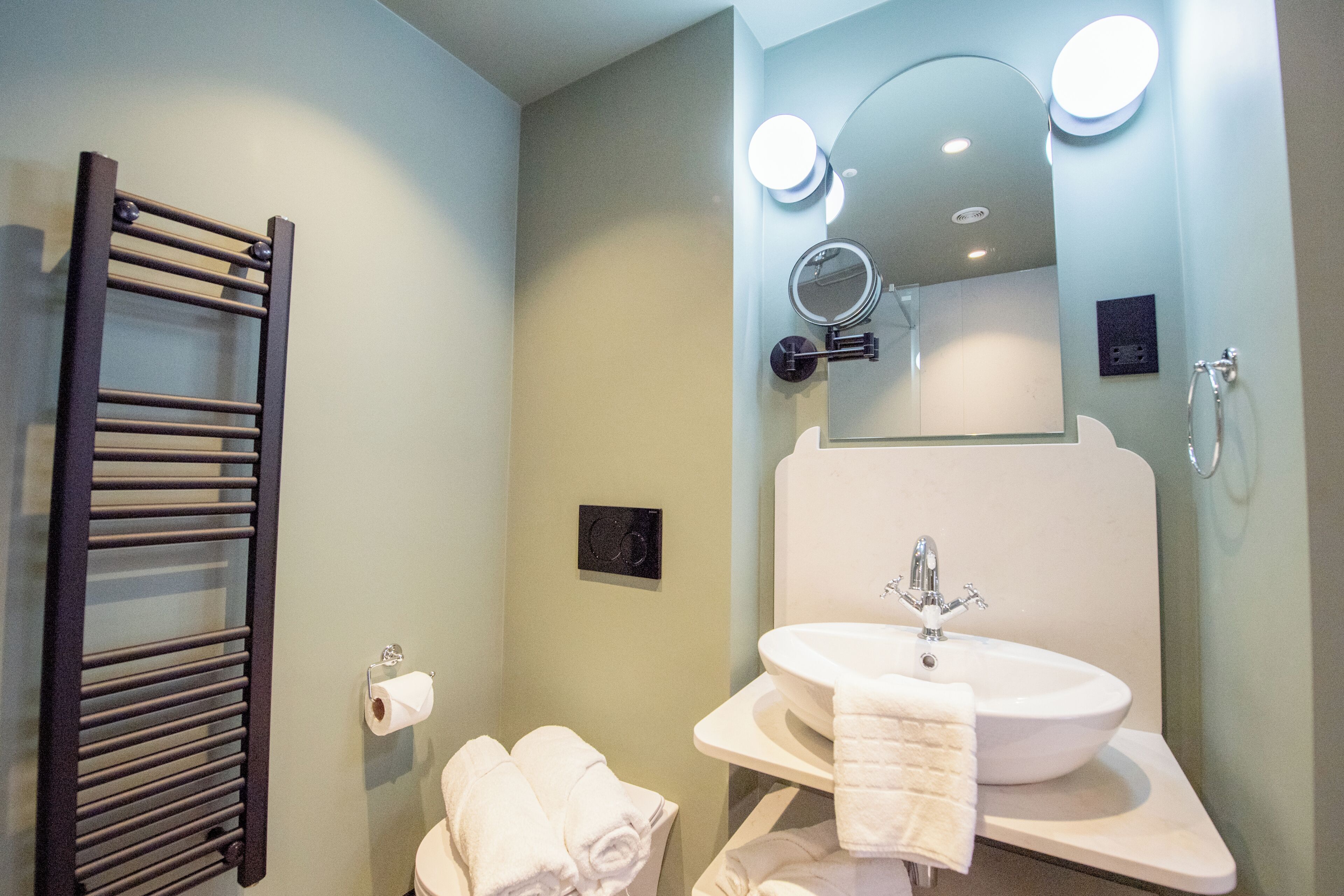 A bathroom with a toilet, a sink, a mirror, and a towel rack.