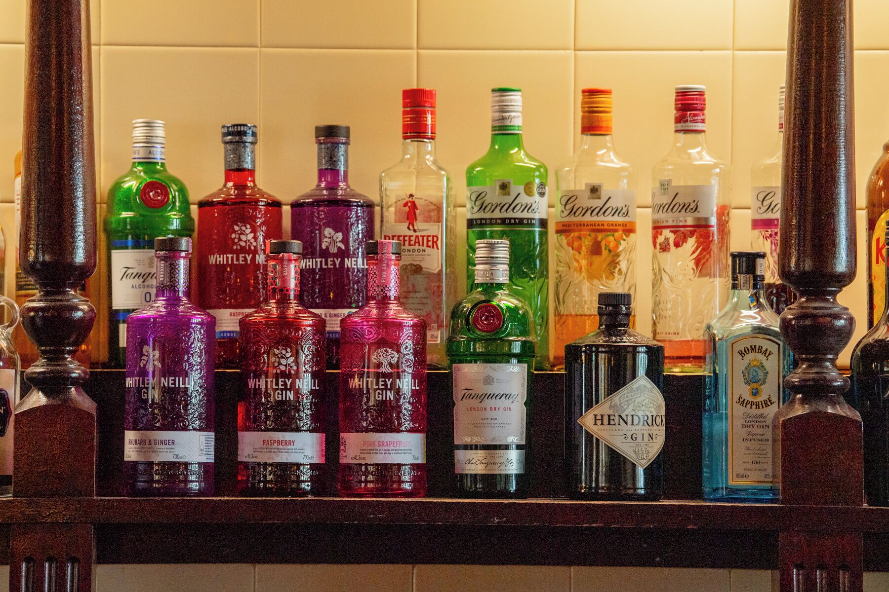 A variety of gin bottles on a shelf.