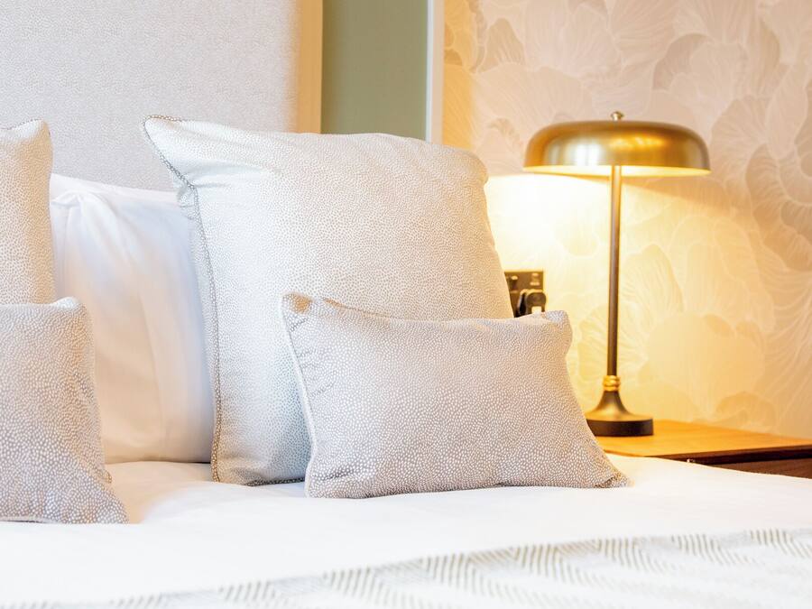 Ein Bett mit vier Kissen und einer Nachttischlampe.