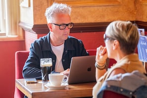 Two people seated at a table with a laptop, a glass of beer, and a cup of coffee. - The Carre Arms Hotel (Sleaford)
