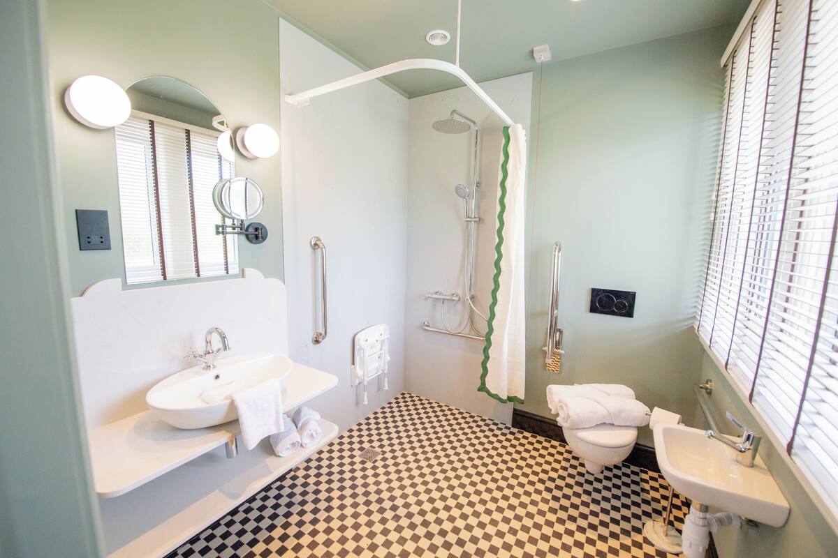 Ein Badezimmer mit Schachbrettboden, einer Dusche, einem Waschbecken und einer Toilette.