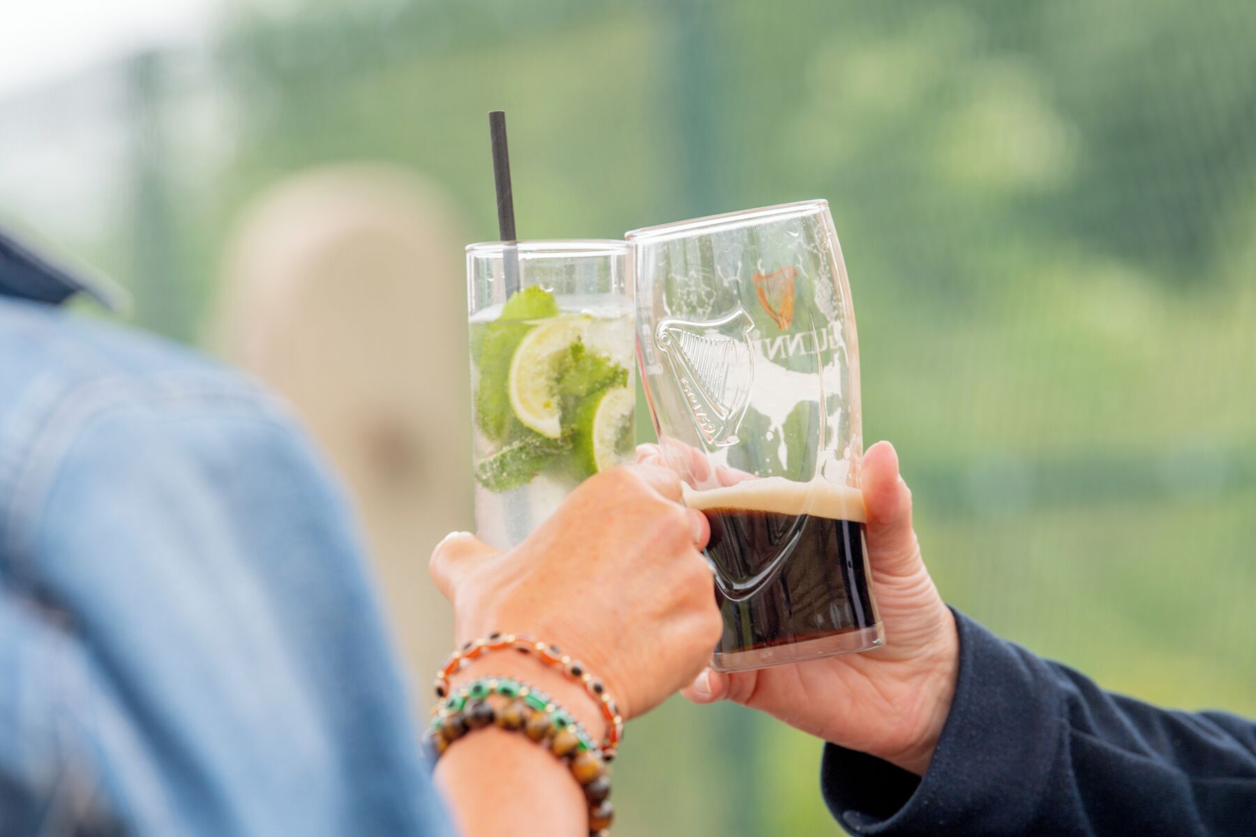 Two people holding glasses with a beverage, one with a straw.
