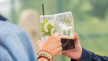 Two people holding glasses with a beverage, one with a straw.