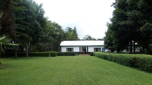 A white building with a flat roof, surrounded by well-maintained grass and hedges.