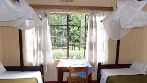 A room with two beds, a table, and a window with curtains.