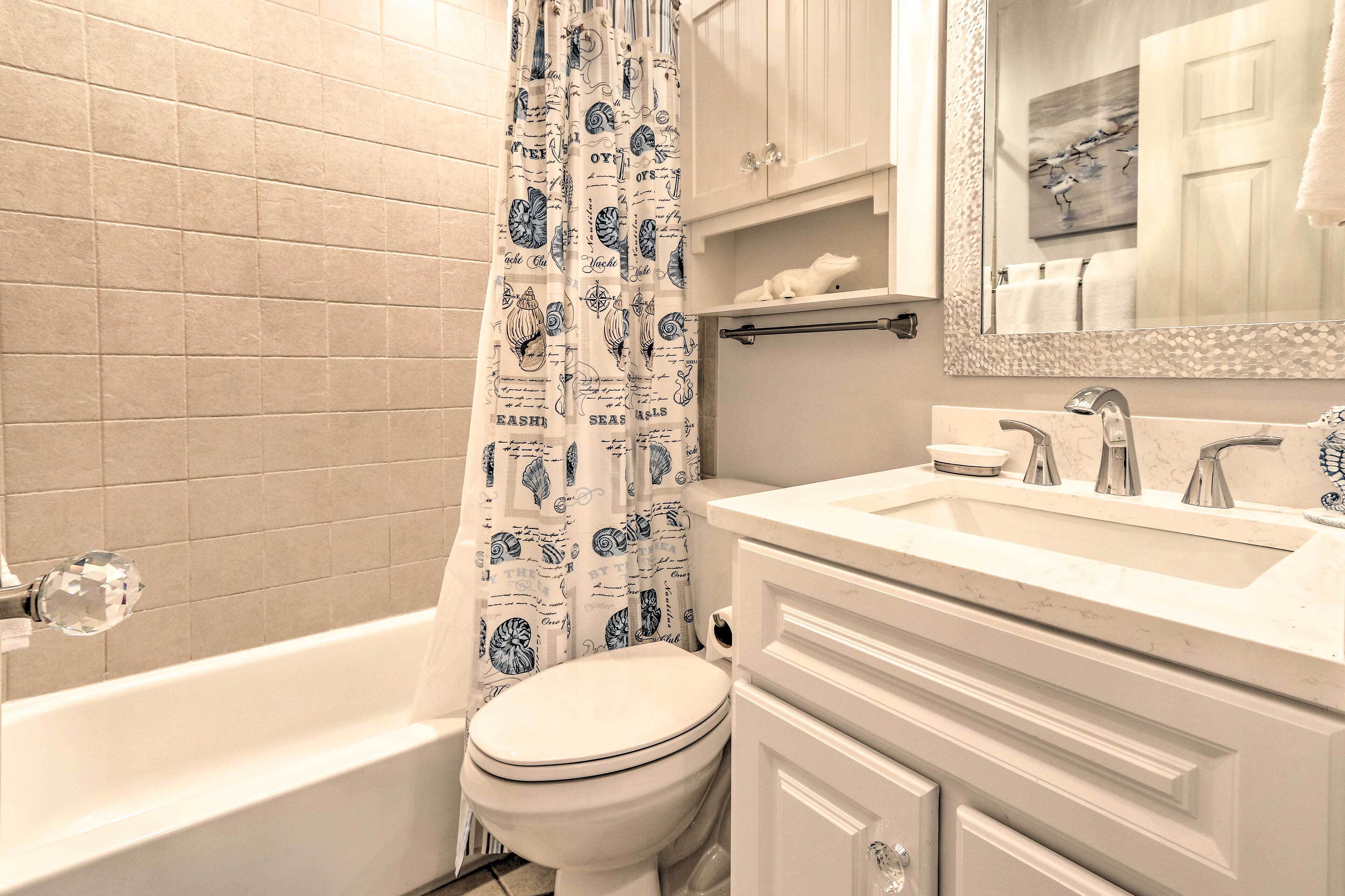 A bathroom with a bathtub, toilet, and vanity with a mirror.