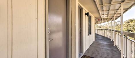 Une véranda couverte avec un plancher en bois et des balustrades blanches.