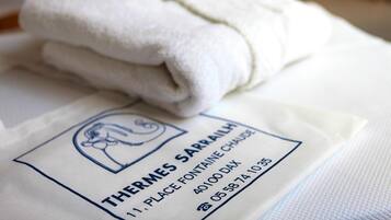 Una toalla blanca doblada sobre una superficie blanca con una etiqueta que dice "THERMES SARRAILH 1 PLACE FONTAINE CHAUSE 40100 DAX 05 58 74 1035".