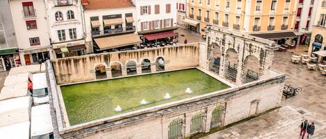 An aerial view of a courtyard with a fountain, surrounded by historic buildings with balconies and shops.