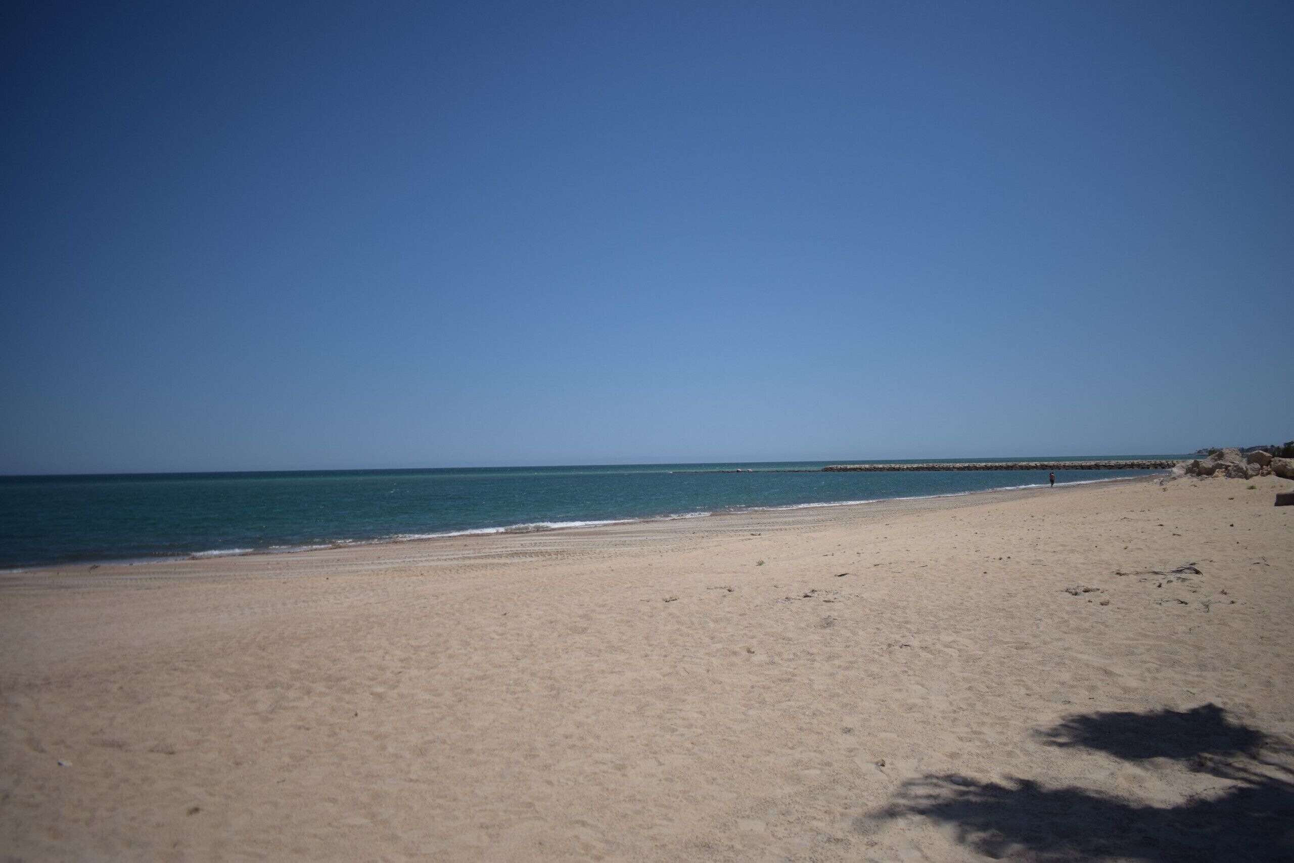 A beach with a clear sky and calm sea.