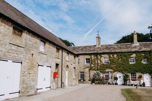 A stone building with a gravel courtyard, white doors, and a chimney. - Hooton Pagnell Hall (Doncaster)